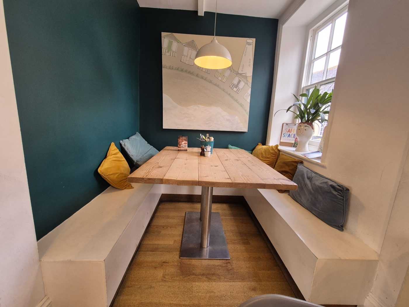 Wooden benches and a table against a teal wall