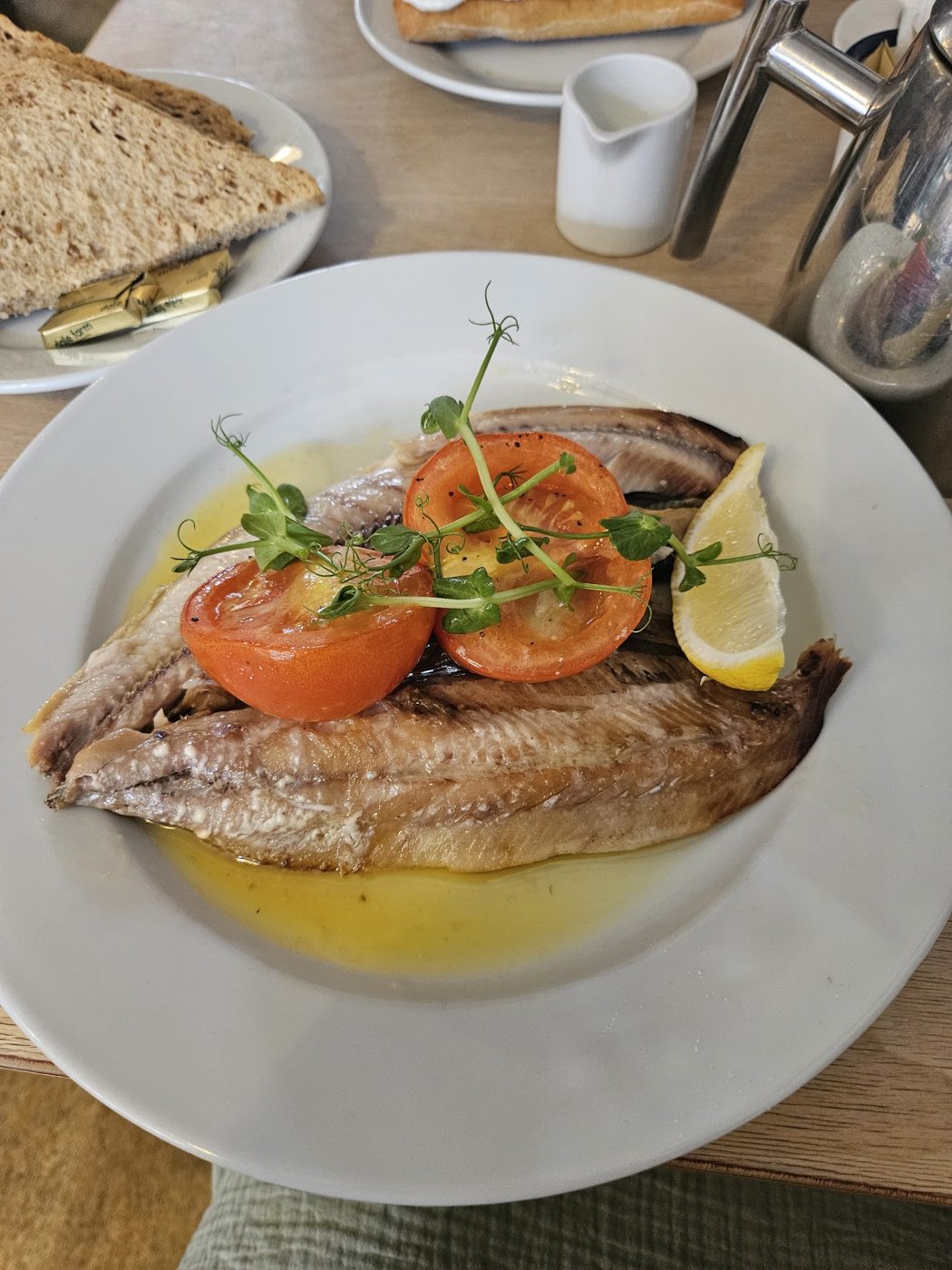 A fish fillet with tomatoes and a lemon wedge