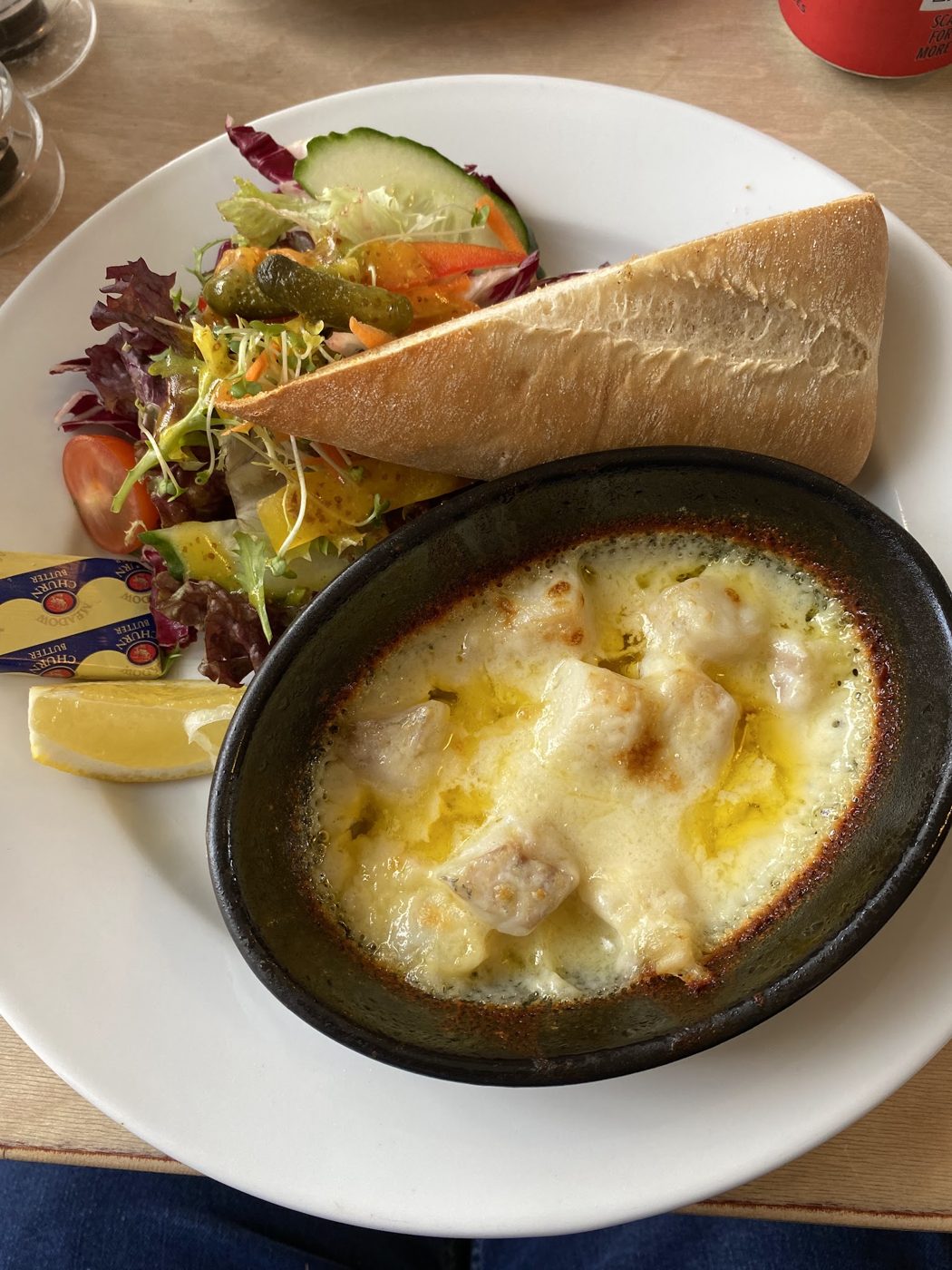 A baked dish in cheese sauce with salad and bread